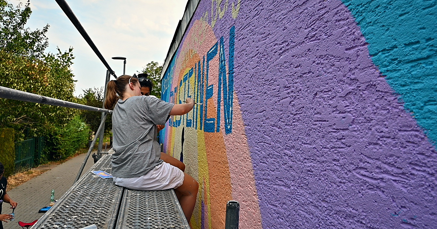 Zwei Helferinnen malen abends den Schriftzug „Edelsteinen“ auf die Wand